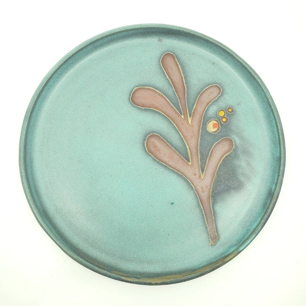 Ceramic dinner plates with a green decorated surface revealing the red clay.