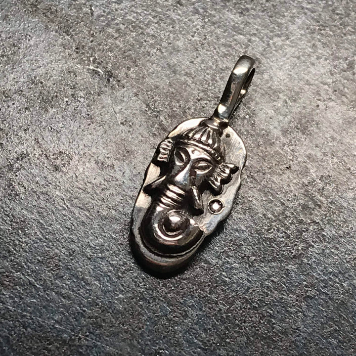 Small Ganesh pendant cast in sterling silver, with a single diamond to the right of the figure