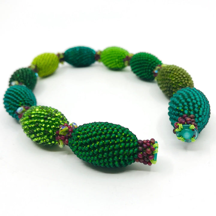 Green Oval Necklace. Green and red glass beads are woven together with green thread. 40cm long.