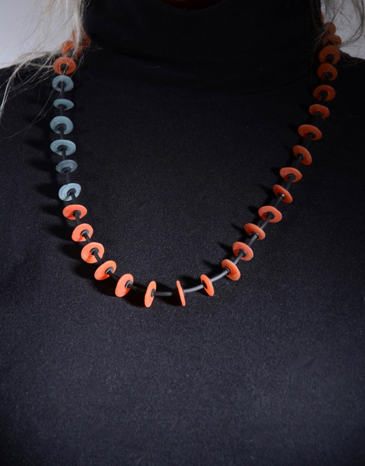 Necklace of stacked flat glass beads in red and grey with black rubber cord, 30". The 40 beads are around 1.5cm in diameter.