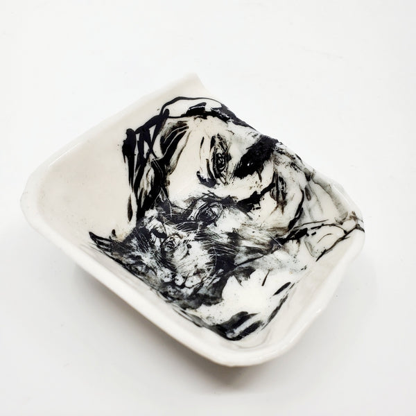Small multi-fired porcelain dish depicting a woman with a cat. The porcelain is translucent when held to the light.