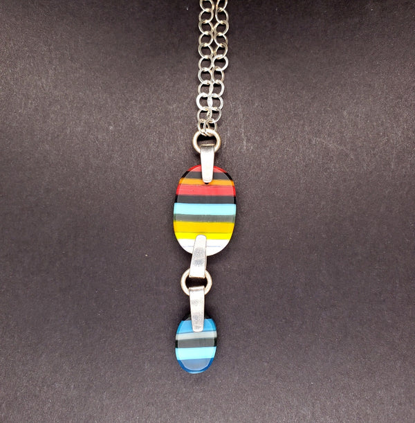 Multicoloured striped carved double-pendant made from kilnformed glass on a 26" sterling silver chain.