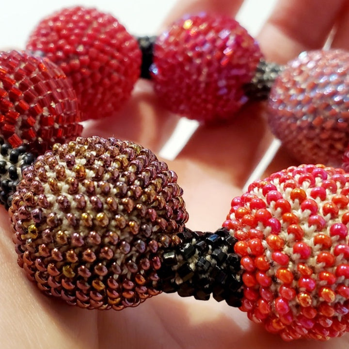 Large Purple Ball Bracelet. Purple and red glass beads are woven together with white thread. Large Purple Ball Bracelet. Purple and red glass beads are woven together with white thread. 