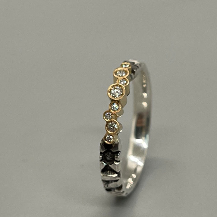 Elegant stamped sterling silver ring with an asymmetrical line of 8 diamonds and 18k gold. 3mm band.