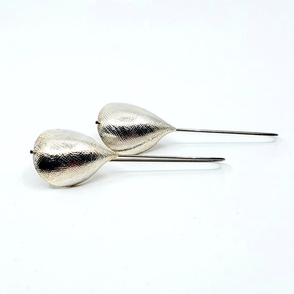 Pinched drop earrings. The textured sterling silver form is threaded on a titanium ear wire that measures 6 x 2 cm.