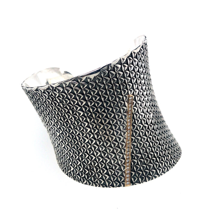 Wide stamped sterling silver cuff bracelets with a line of diamonds set into 18kt yellow gold.