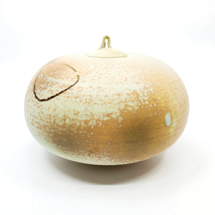 Low jar with lid. This round vessel is speckled pale orange. 