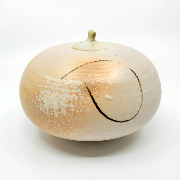 Low jar with lid. This round vessel is speckled pale orange. 