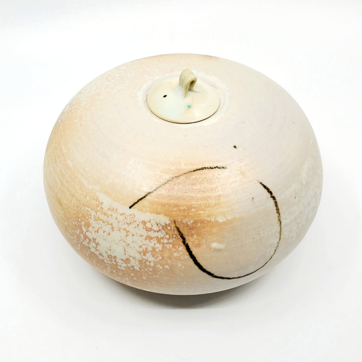 Low jar with lid. This round vessel is speckled pale orange. 