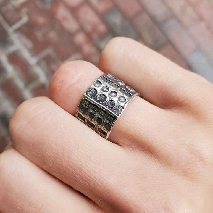 "Hommage à Walter Schluep" : Wide 13mm sterling silver band with stamped patterns circling the entire form. The stamped patterns can be seen also on the inside of the band.