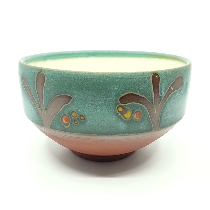 Large green ceramic salad bowl with a tactile decorated surface revealing the red clay. The interior is glazed white.