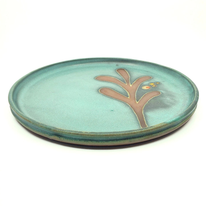 Ceramic dinner plates with a green decorated surface revealing the red clay.