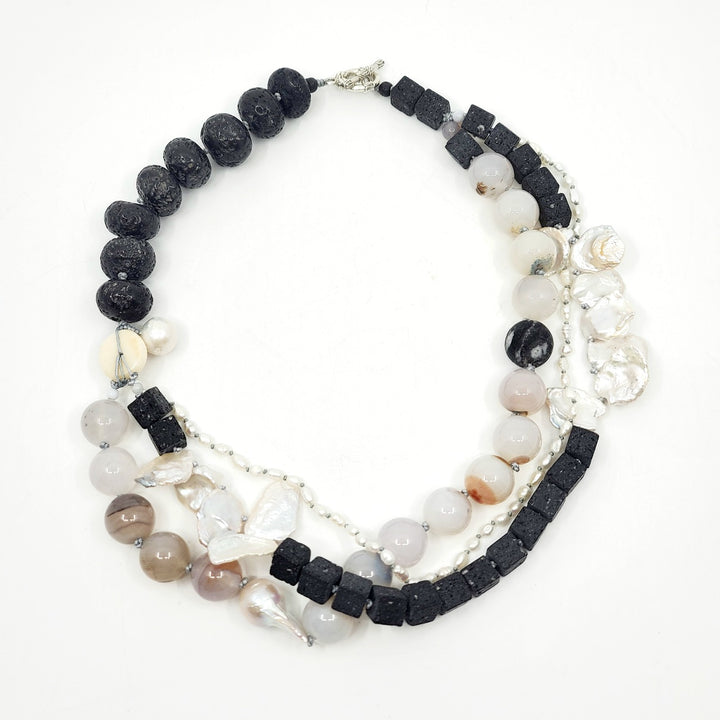 Multi-strand necklace of lava stones, agate, and baroque pearls, hand-knotted between each bead, with a sterling silver clasp.