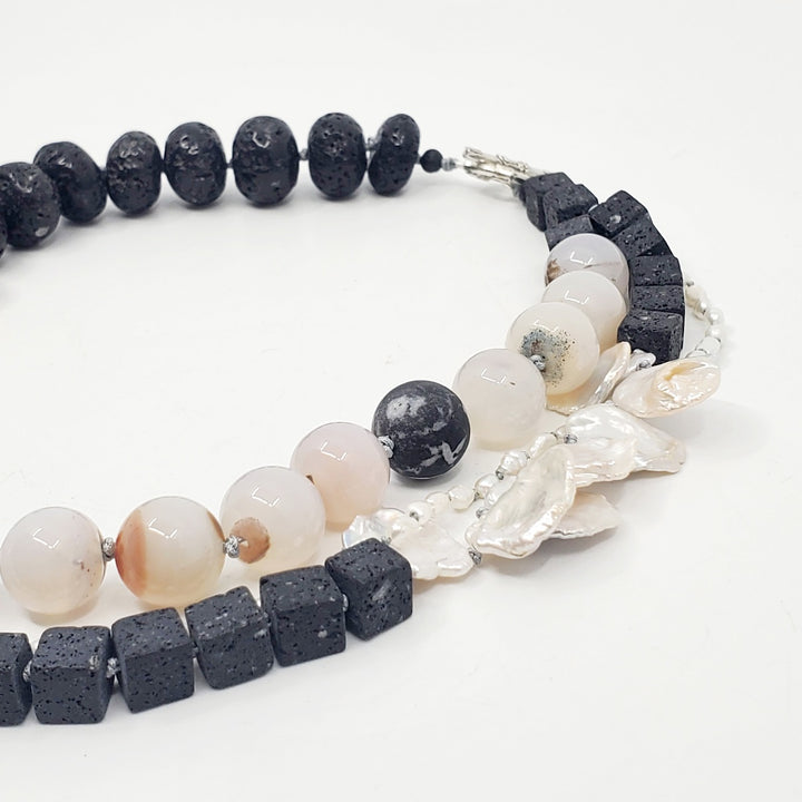 Multi-strand necklace of lava stones, agate, and baroque pearls, hand-knotted between each bead, with a sterling silver clasp.