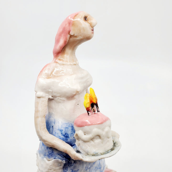 Cake Wife: Two-part ceramic sculpture of a woman holding a cake, and an oven. Designed to hang on the wall, each hangs separately from a metal loop.
