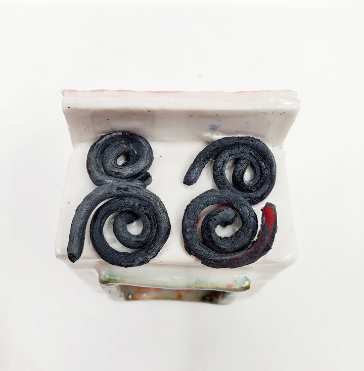 Cake Wife: Two-part ceramic sculpture of a woman holding a cake, and an oven. Designed to hang on the wall, each hangs separately from a metal loop.