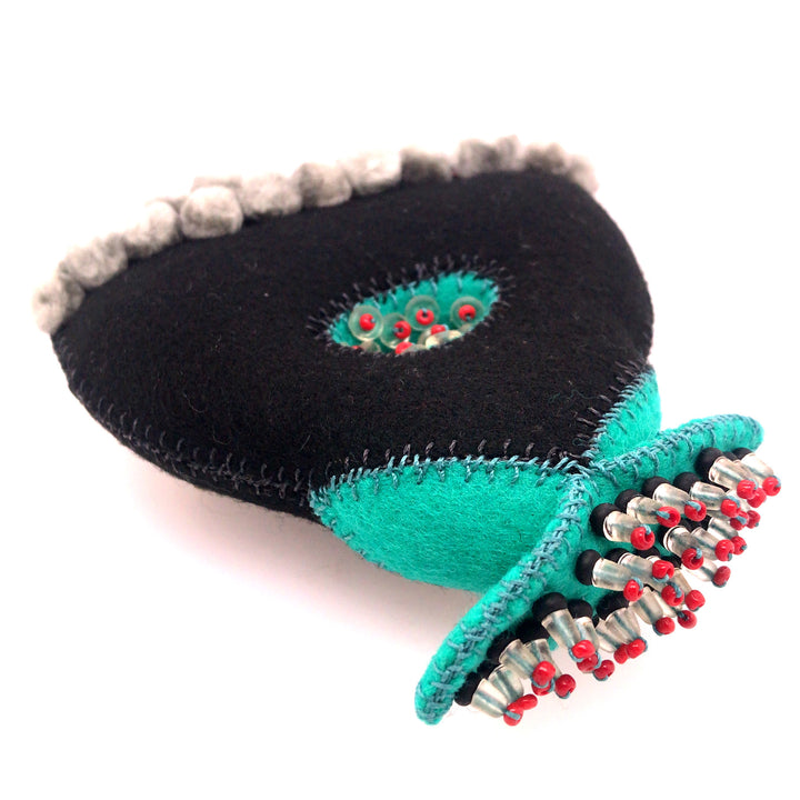 Black and turquoise wool brooch with glass beads and thread.