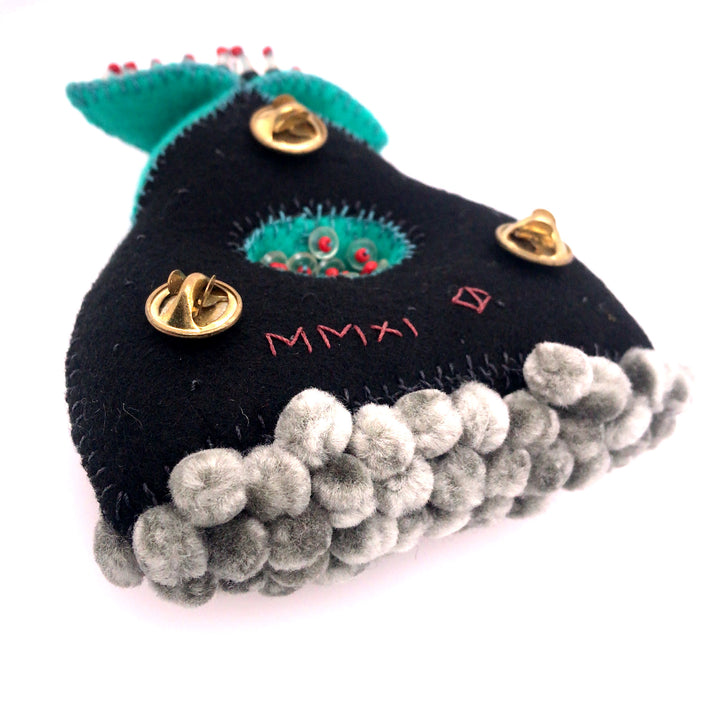 Black and turquoise wool brooch with glass beads and thread.