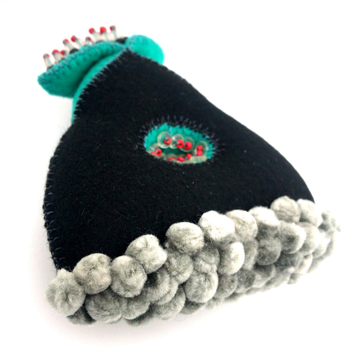 Black and turquoise wool brooch with glass beads and thread.
