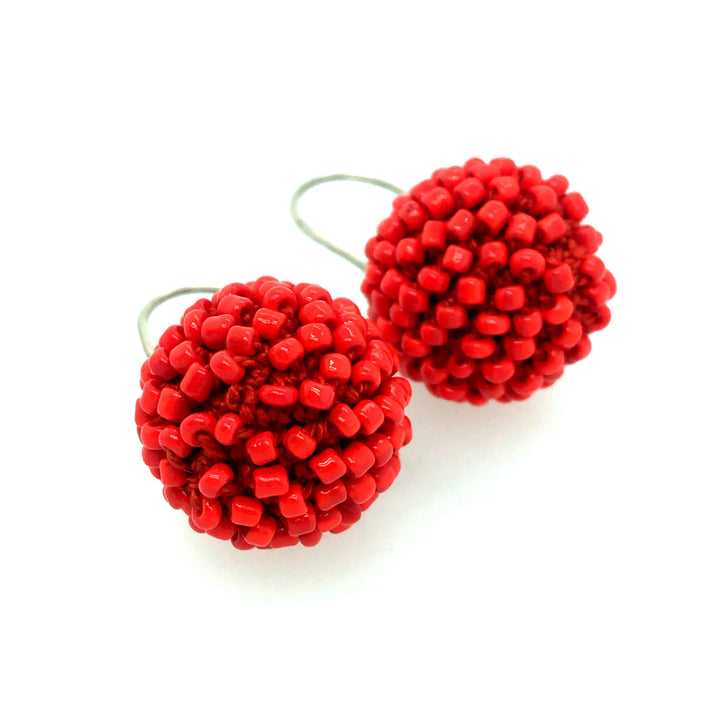 Short Orange Earrings. Red-orange glass beads are sewn in with red thread. 