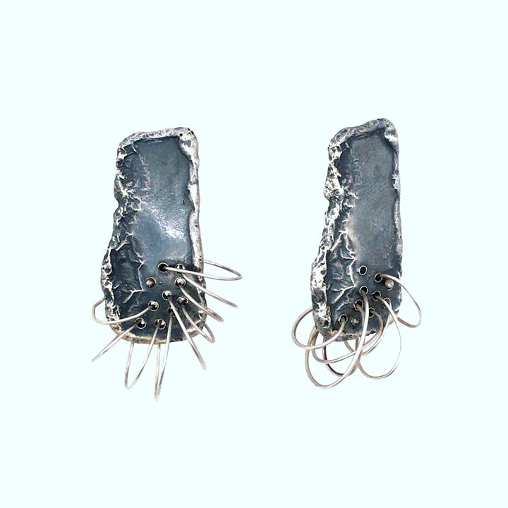 Monomanies motrices stud earrings of sterling silver.