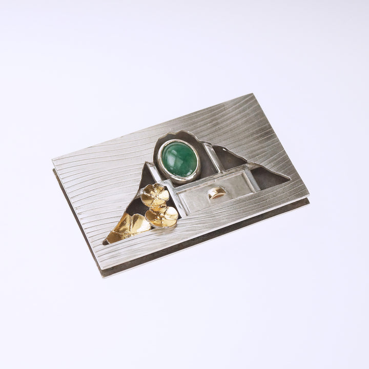 Hometown: Taiwan Duobaoge (curio boxes) - Silver Brooch, 2022.  Created with cold connection (riveting, rolling printing, bezel setting, oxidation, and Keum-boo, this brooch is made of sterling silver, 18k yellow gold, gold foil, and jade. The inside elements can be customized.  6x3.6x0.7cm