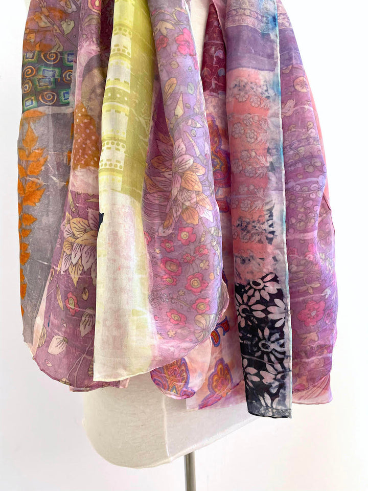 Light and colourful patterned silk scarf in hues of purple and green. The artist uses an innovative transfer technique to create each one-of-a-kind piece.