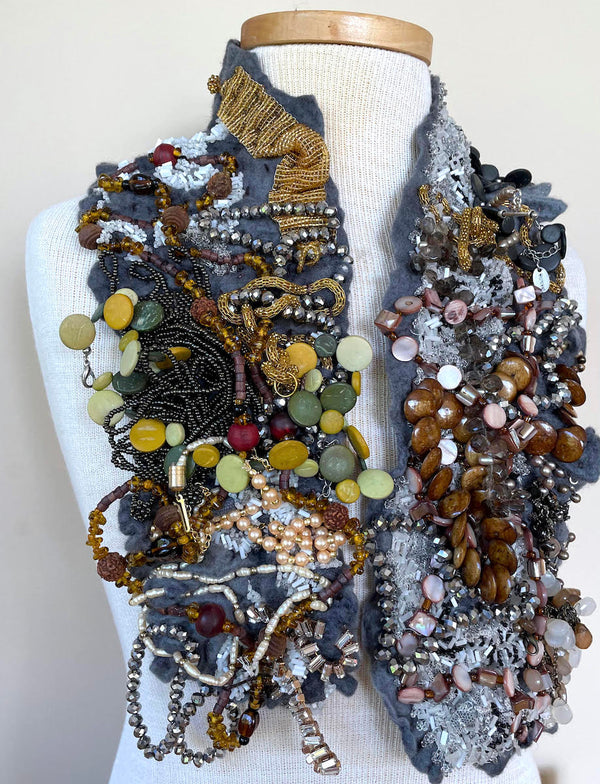 This shimmering felted neckpiece incorporates swatches of beaded fabrics and jewellery to make a bold statement. The grey felted underside is soft against the skin, with a comfortable weight.
