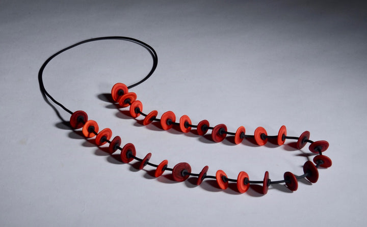 Necklace of flat glass beads in bright and dark red with black rubber cord, 33". The 28 beads are around 1.5cm in diameter.