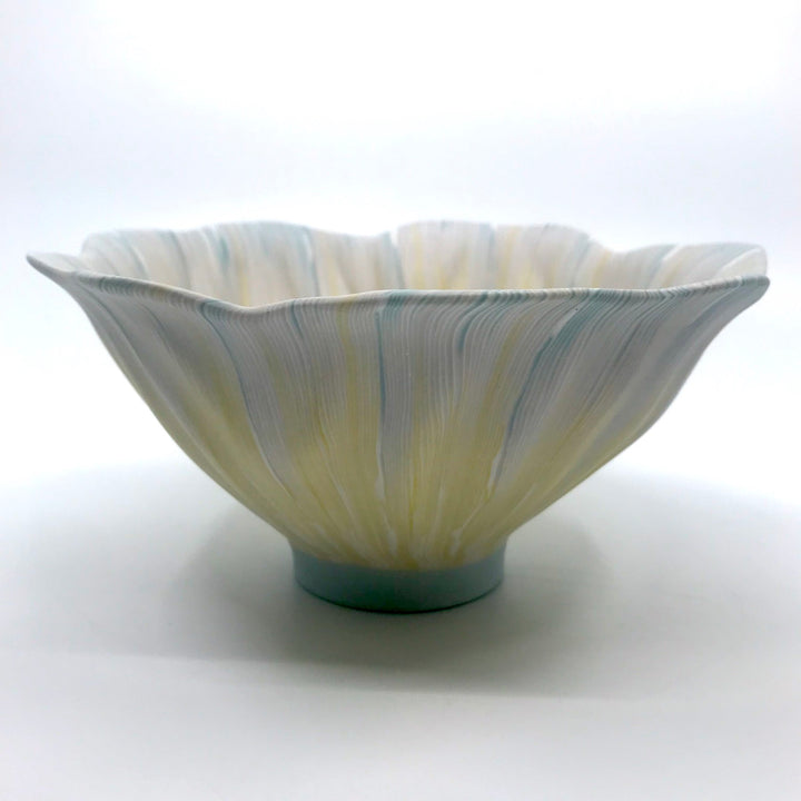 Multicolour ceramic bowl with strands of yellow extending from the center to the blue-tinged edges, made with the nerikomi ceramic technique.