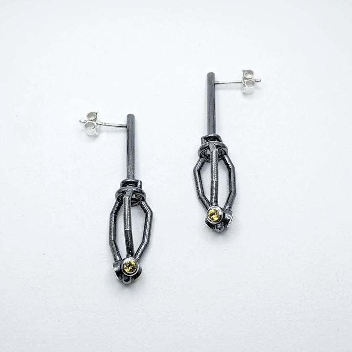 Earrings No. 28272908, from the Seed Collection. 2023.   Created with algorithmic design, 3D printing, and stone setting, these earrings are made of oxidized sterling silver and yellow sapphires.  6x2x1.5cm each