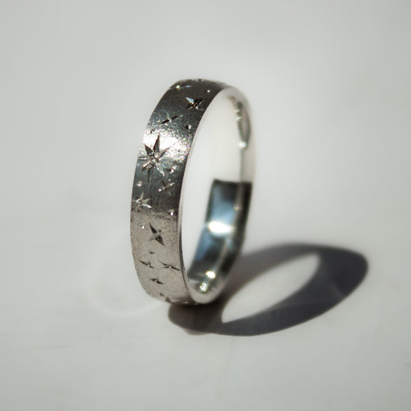Silver ring with textured design on a light gray background