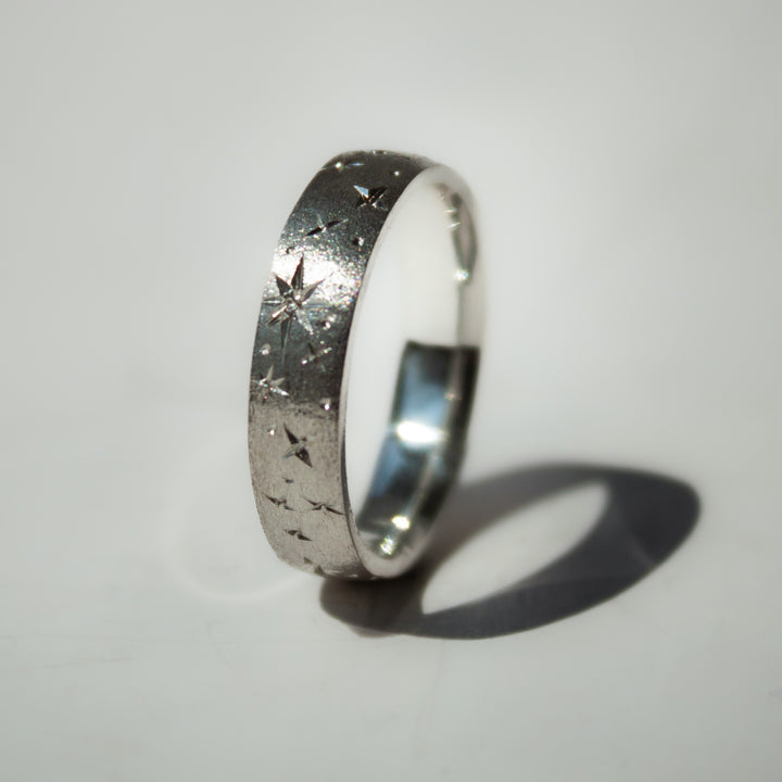 Silver ring with textured design on a light gray background