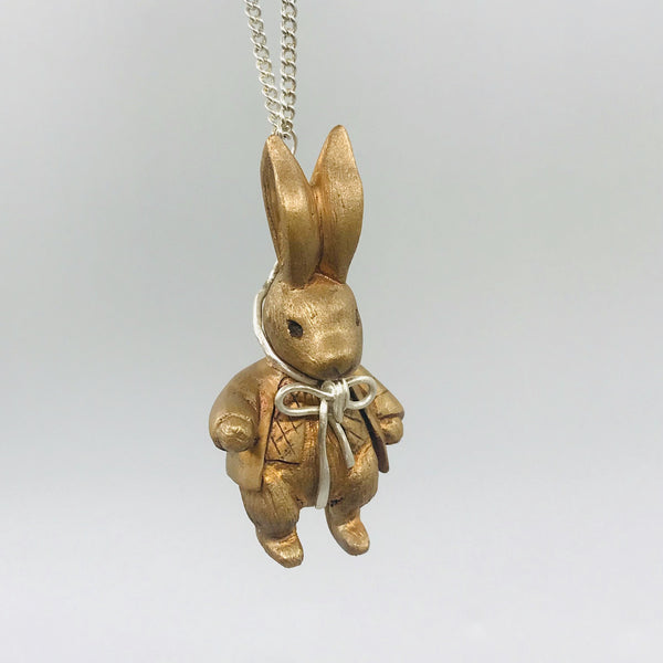 Gold rabbit-shaped pendant on a chain against a light gray background