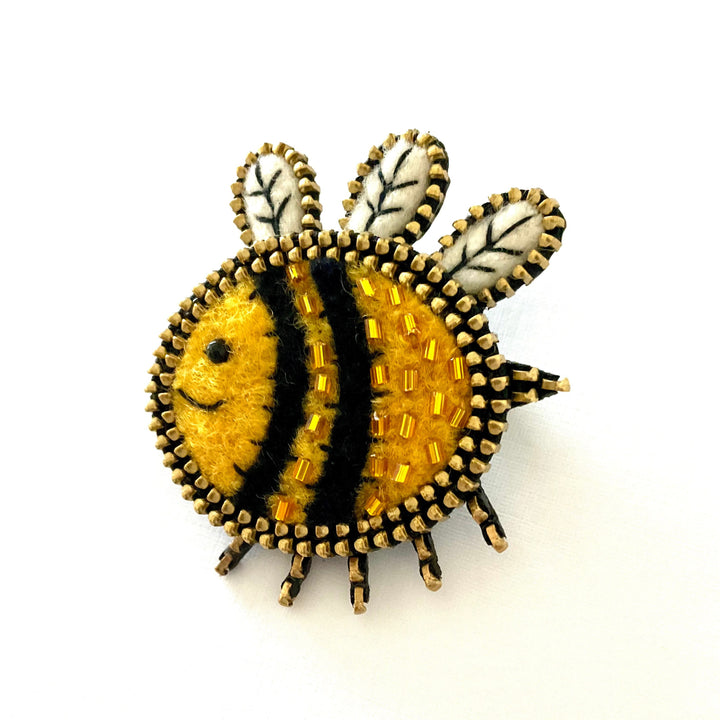 Bee-shaped brooch with yellow and black stripes on a white background