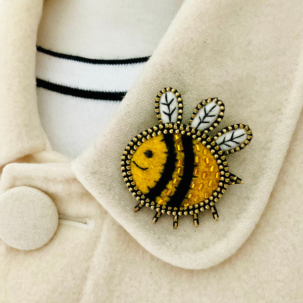 Bee-shaped brooch on a beige coat with a white background