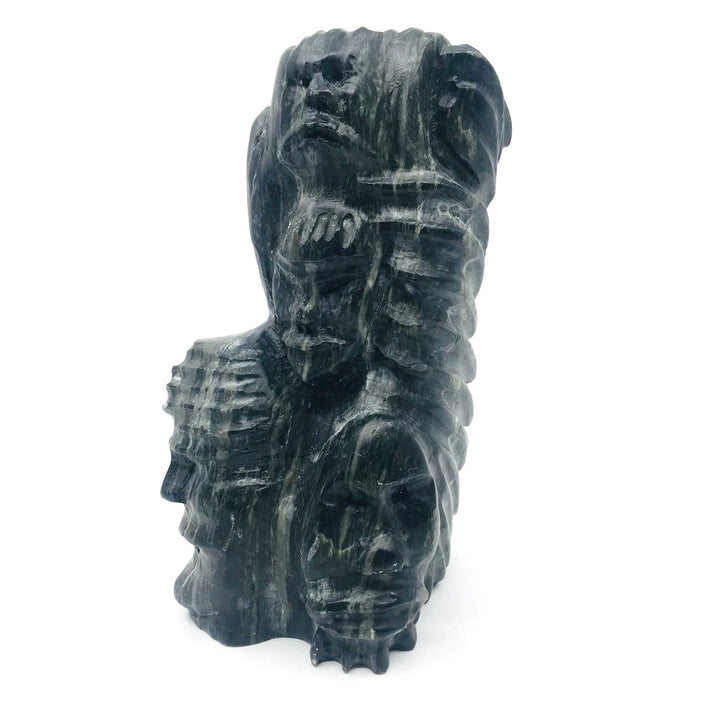 Faces in black serpentine carving by Silas Aittauq