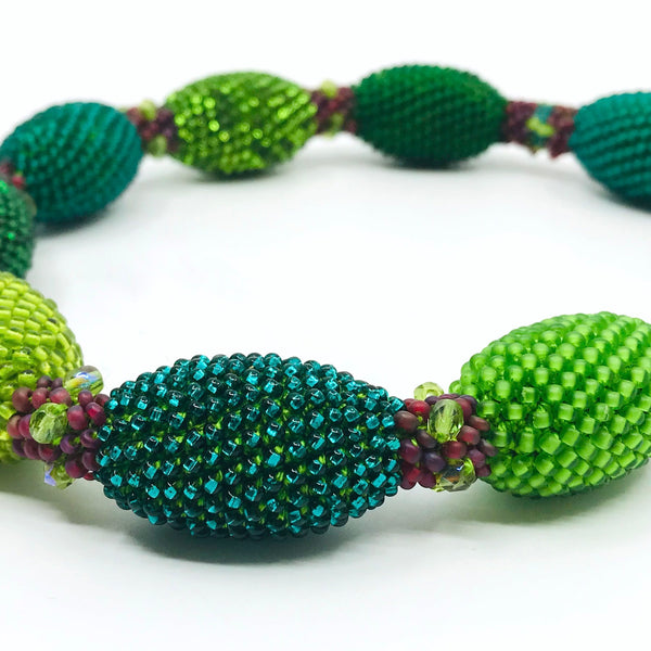 Green Oval Necklace. Green and red glass beads are woven together with green thread. 40cm long.
