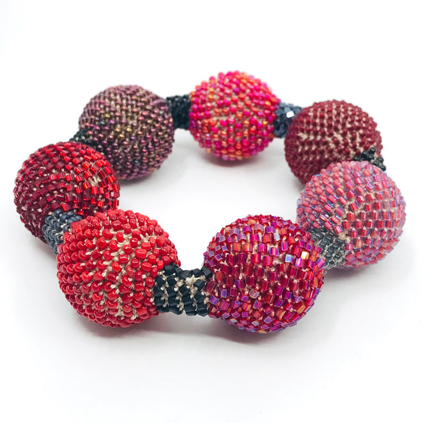 Large Purple Ball Bracelet. Purple and red glass beads are woven together with white thread. 