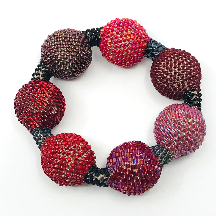 Large Purple Ball Bracelet. Purple and red glass beads are woven together with white thread. 