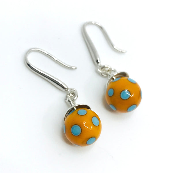 Flame-worked glass polka dot earrings in orange and blue.