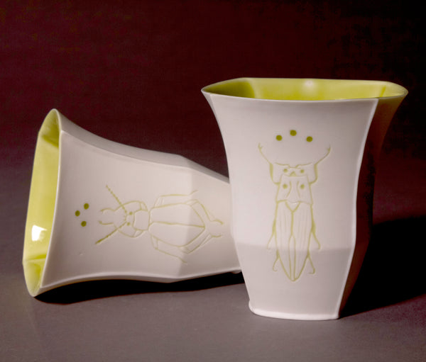 Tall slip-cast cups of translucent porcelain with etched beetles