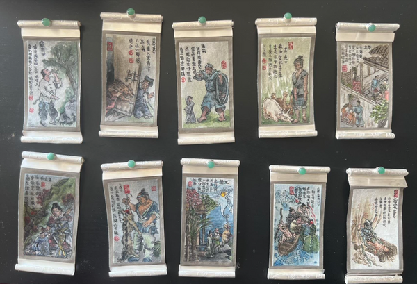 Set of small scroll painting brooches with various scenes and characters on a black background