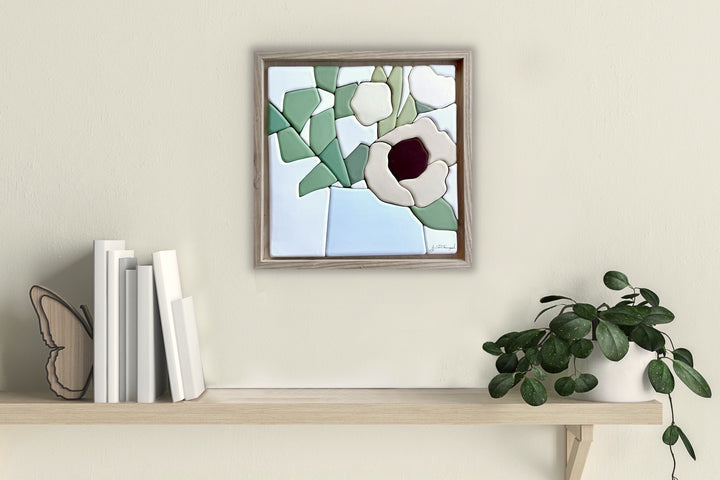 Sit for a Minute! - Hand molded clay coloured pieces within a solid wood frame, depicting a still life of warmly coloured flowers.