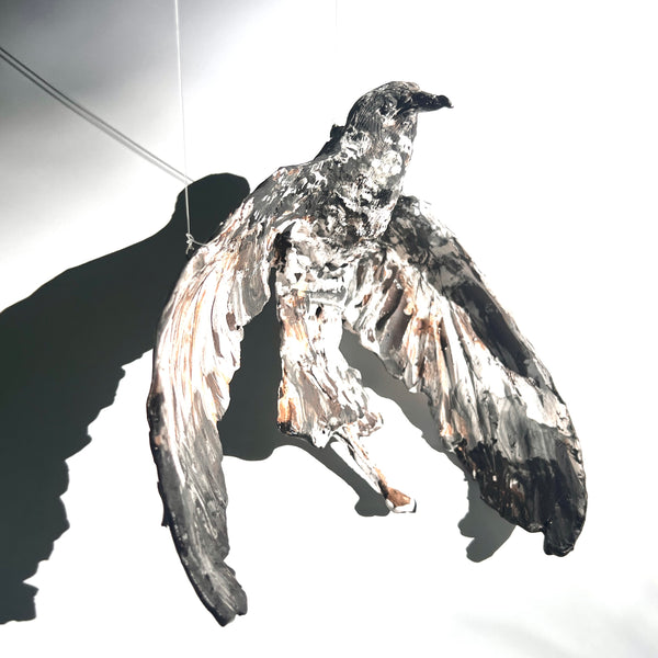 Parasitic Jaeger in Flight - wings rounded : multi-fired porcelain suspended sculpture of a jaeger in flight, its wings and tail curved against the wind. The surface is richly decorated with texture.