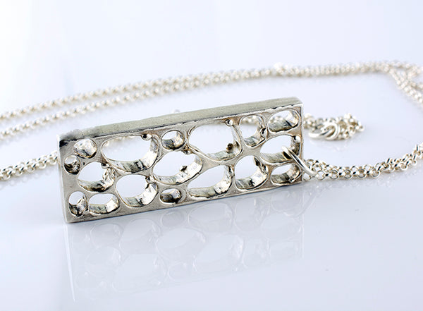 Silver necklace with a detailed pendant on a light background