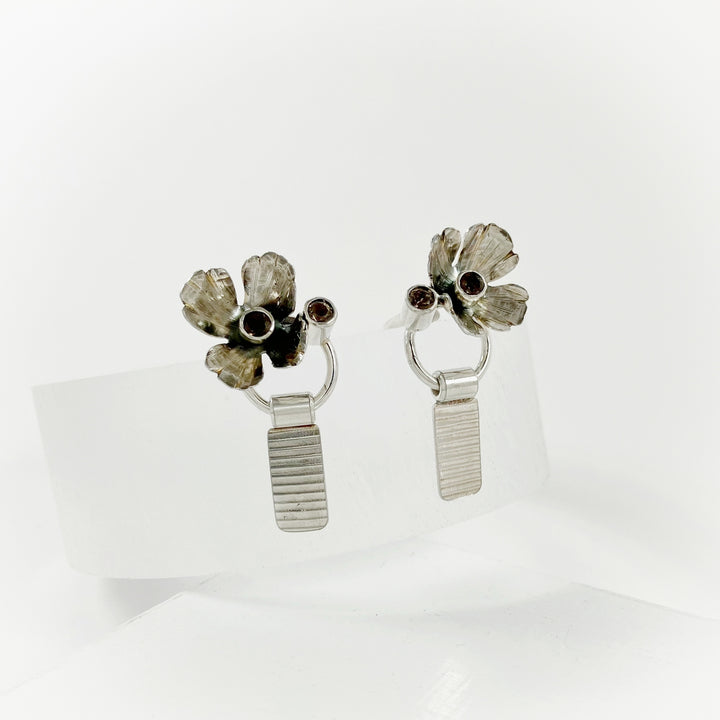 Pair of silver floral earrings on a white background
