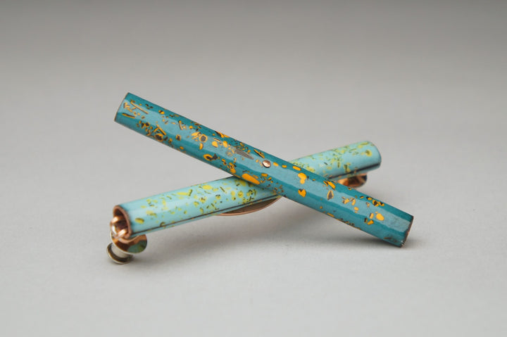 Handle, 2023.  Created with hand fabrication and enamelling, this brooch is made of copper, enamel, nickel, and steel.  8.3 x 2.4 x 1.8cm (8.3 x 2.4 x 8cm when opened)