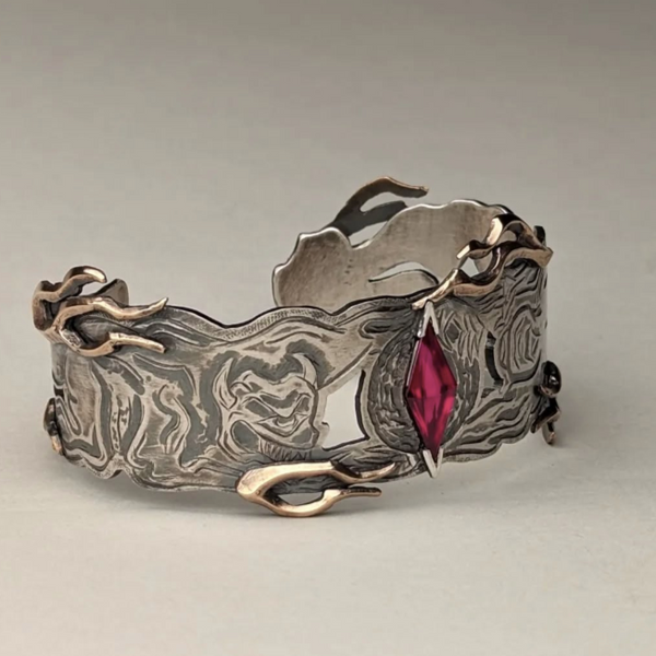Silver bracelet with a red gemstone on a light gray background
