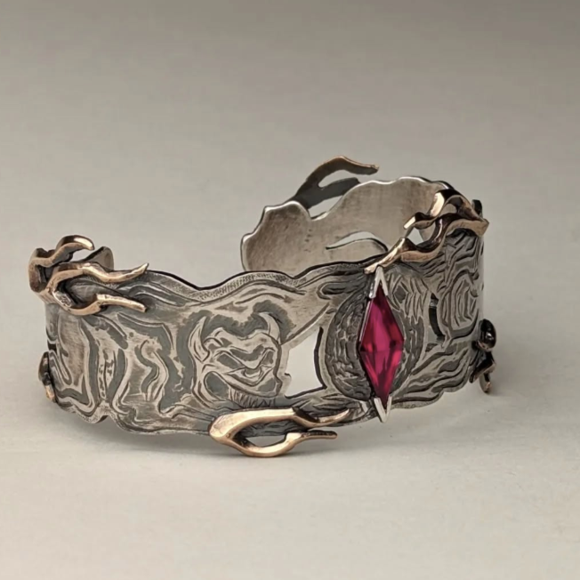 Silver bracelet with a red gemstone on a light gray background